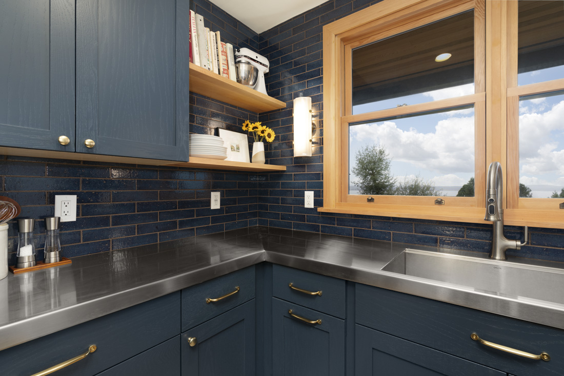 A kitchen with deep blue backsplash and cabinetry represents the home design trends of incorporating rich color into spaces or rooms.