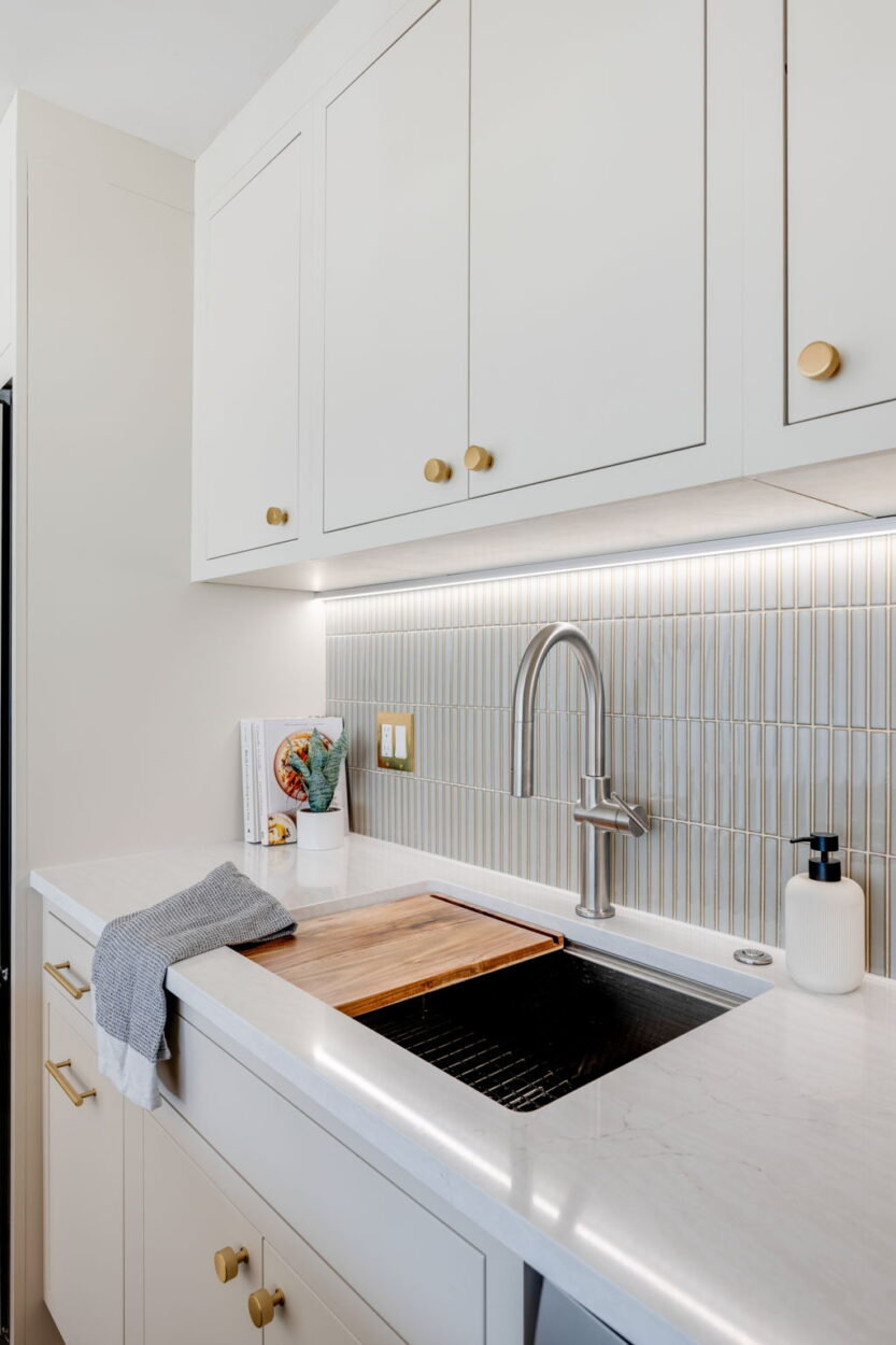 A modern kitchen remodel displays 2025 trends by mixing metals with copper cabinet pulls, a gold switch plate, and a stainless steel faucet. 