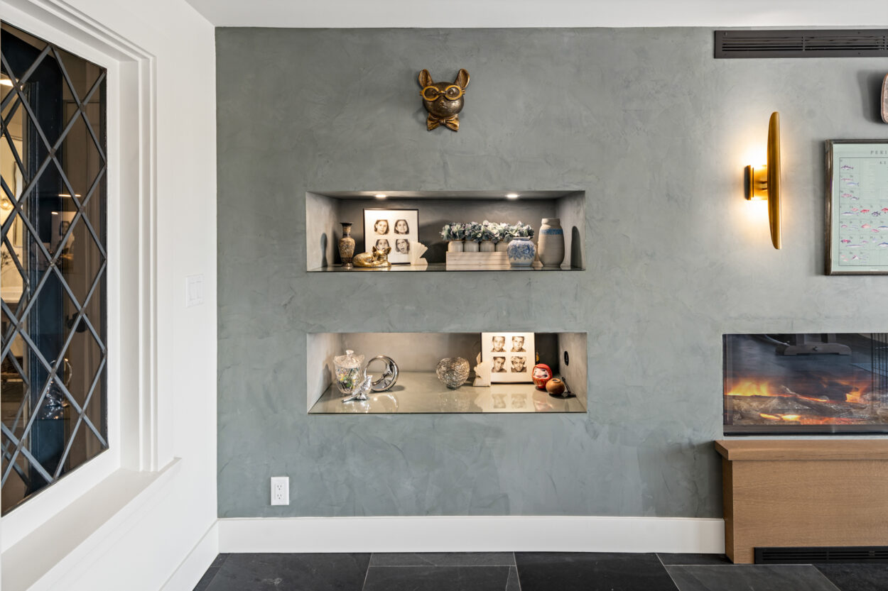 Creative plaster application and gray paint on this living room accent wall create an almost concrete look. 2025 design trends include textured accents, so this remodel is the perfect example. 