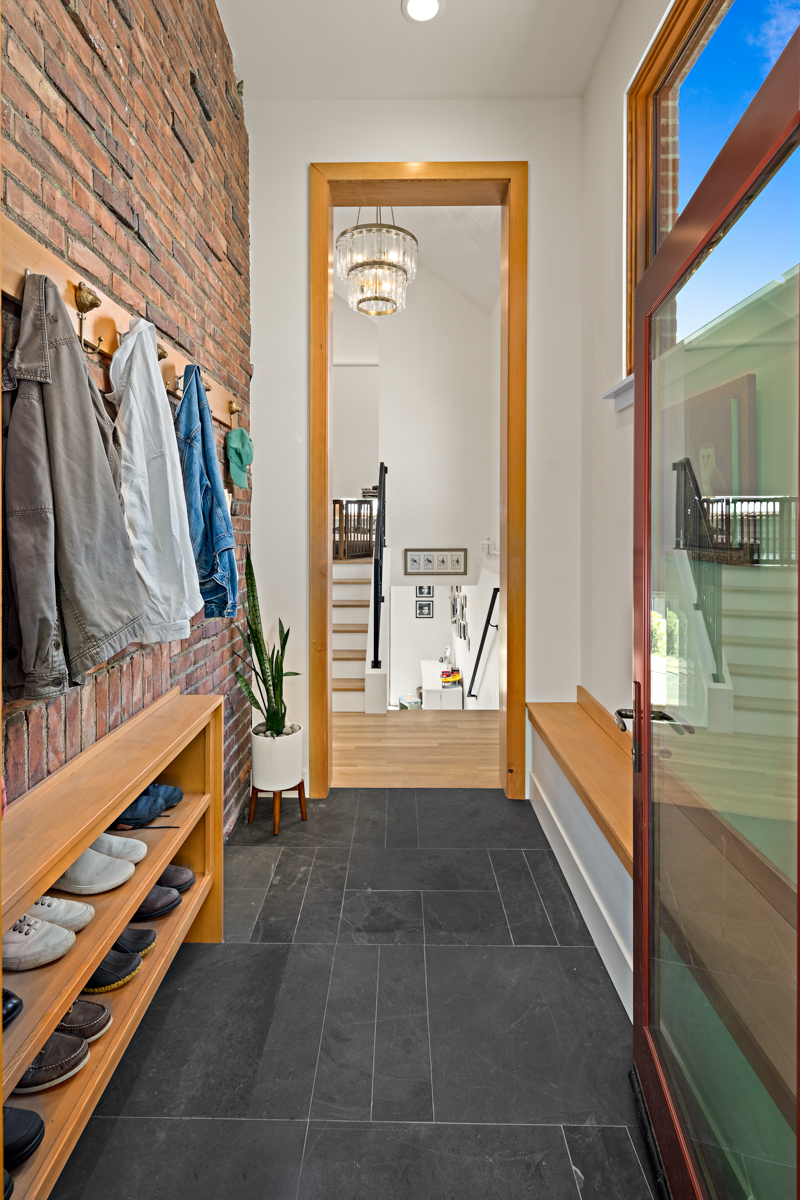 Design trends for 2025 include incorporating natural stone materials into your home. This mudroom features natural black stone tiling on the floor and brick on the wall to flawlessly execute this trend.