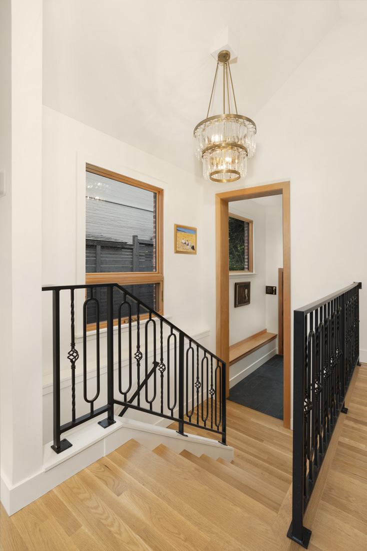 2025 design trends list statment lighting as a way to create unexpected visual interest to a space. This stairwell accomplishes this by featuring a vintage tiered crystal chandelier to stand out from the warm wood tone flooring and wrought iron railing.