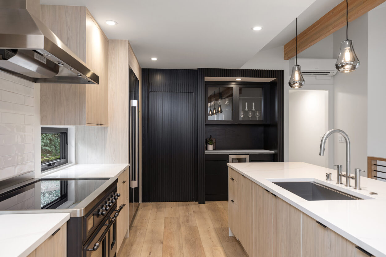 This trendy kitchen of course belongs in a gallery of 2025 home design trends. Light wood and soft white counters create an overall softness, while rich black slats create a statement wall to house a bar and hidden pantry while adding drama and a completely unique look. 