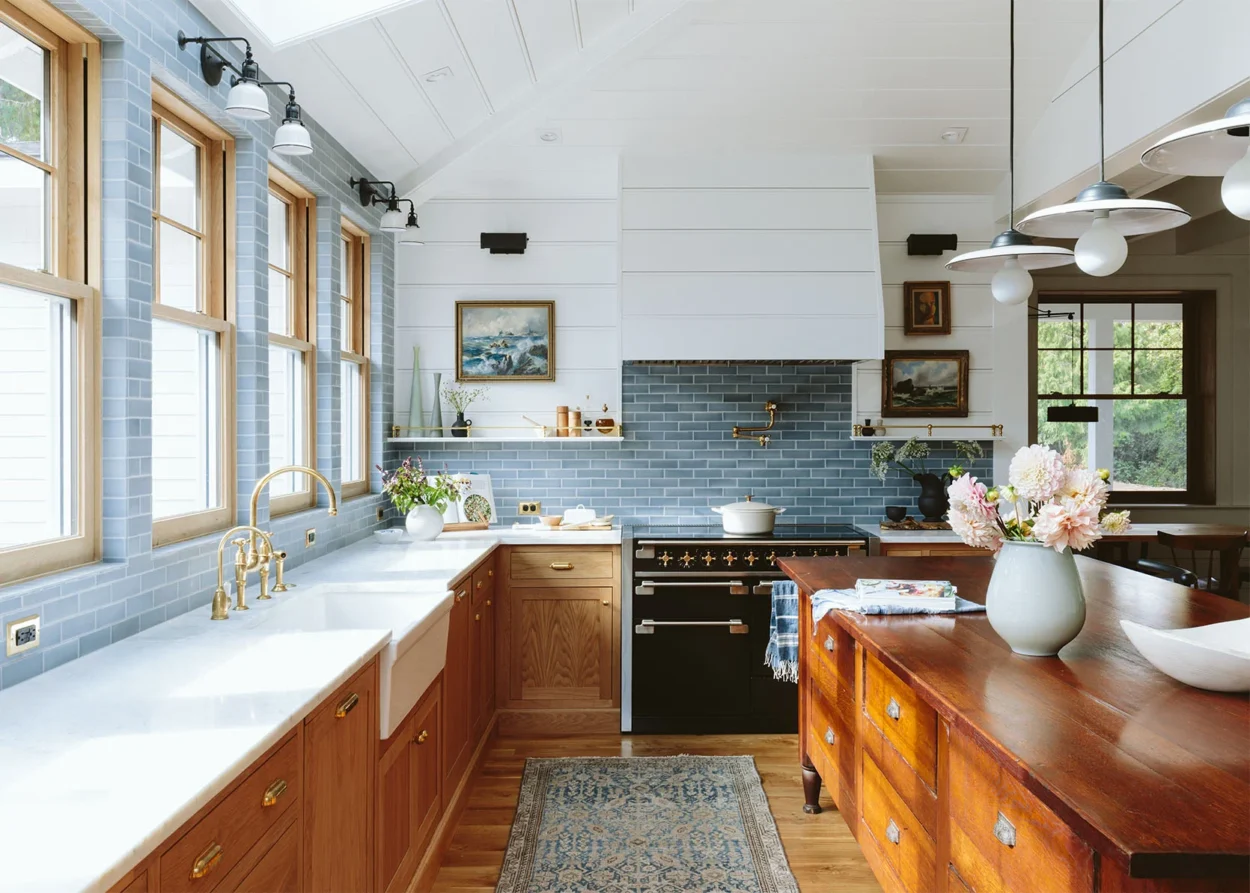 A kitchen featuring rich wood, bright white, colorful tiling, and wood slats is a perfect example of the modern cottage aesthetic of 2025 design trends.