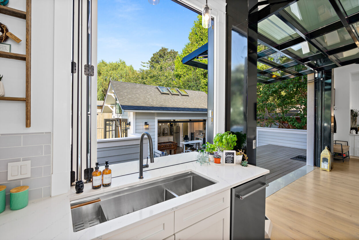 An oversized awning window provides a seamless flow between indoor and outdoor spaces, doubling as a covering for outdoor dining, showcasing innovative outdoor remodeling.